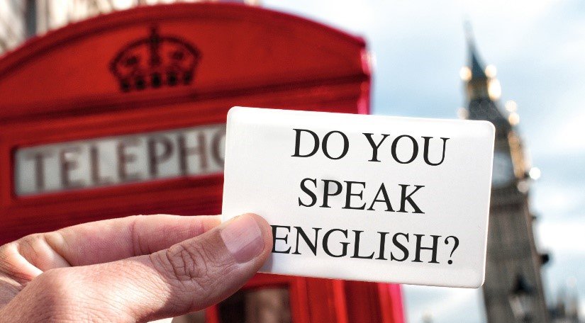 Hier wird vor einer für London typischen roten Telefonzelle ein weißes Papier mit der Aufschrift "Do you speak English" gehalten.