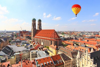 Aufdem Bild sind die Dächer von München zu sehen. Im Himmel befindet sich ein Heißluftballon.